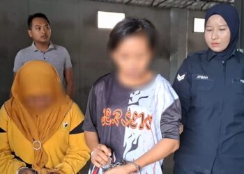 SEORANG wanita (kiri) direman tujuh hari bagi membantu siasatan kes rogol anaknya dibawa keluar dari Mahkamah Majistret Kemaman, hari ini. - UTUSAN/NIK NUR IZZATUL HAZWANI NIK ADNAN