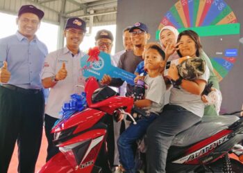 ABDUL RASHID Bahri (dua dari Kiri) menyampaikan hadiah cabutan bertuah sebuah motosikal kepada pemenang, Mohd. Shafiq Mazlan dan keluarganya pada Program Go Cashless@Pasar Tani Kekal Datin Halimah, Larkin, Johor Bahru.
