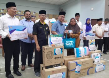 MOHD. NA'IM Mokhtar (tengah) menyampaikan sumbangan kepada seorang mangsa pada Misi Bantuan Pasca Banjir Agensi di bawah Menteri di Jabatan Perdana Menteri (Hal Ehwal Agama) di Dewan Kampung Sungai Telor, Kota Tinggi.