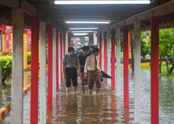 SEKUMPULAN pelajar meredah banjir di SMK Agama Sheikh Abdul Malek, Kuala Terengganu, hari ini. - UTUSAN/PUQTRA HAIRRY ROSLI