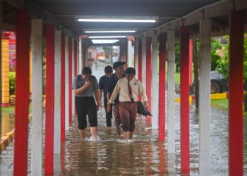 SEKUMPULAN pelajar meredah banjir di SMK Agama Sheikh Abdul Malek, Kuala Terengganu.  - UTUSAN/PUQTRA HAIRRY ROSLI