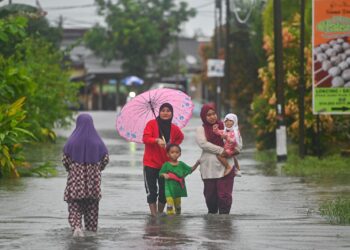 PENDUDUK meredah banjir di Jalan Kamaruddin, Kuala Terengganu, semalam.  - UTUSAN/PUQTRA HAIRRY ROSLI