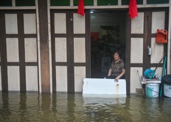 PENDUDUK, Lee Keng Ge melihat paras air di hadapan rumahnya selepas hujan lebat di Lorong Gemia, Kuala Terengganu, semalam. - UTUSAN/PUQTRA HAIRRY ROSLI