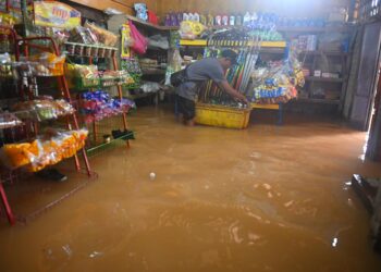 SEORANG peniaga kedai runcit memindahkan barangan perniagaan setelah dinaiki air dalam kejadian banjir di Kampung Nibong, Hulu Terengganu, semalam. - UTUSAN/PUQTRA HAIRRY ROSLI