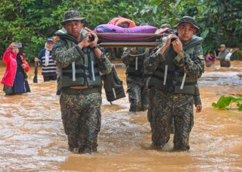 ANGGOTA ATM meredah banjir mengusung jenazah Kelthom Mat yang meninggal akibat sakit tua untuk urusan pengebumian di Kampung Bukit Tadok, Hulu Terengganu, hari ini. - UTUSAN/PUQTRA HAIRRY ROSLI