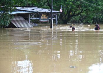BEBERAPA remaja meredah banjir di Kampung Belimbing, Hulu Dungun, Dungun, semalam. - UTUSAN/PUQTRA HAIRRY ROSLI