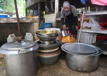 SEORANG pembantu Restoran Mat Binjai menunjukkan periuk yang tidak dapat dibasuh kerana bekalan air terputus di bandar raya Kuala Terengganu, hari ini. - UTUSAN/PUQTRA HAIRRY ROSLI