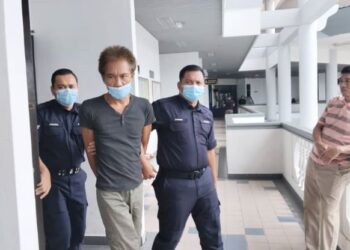 TERTUDUH diiringi polis ketika dihadapkan ke Mahkamah Majistret Ayer Keroh, Melaka. - UTUSAN/MUHAMMAD SHAHIZAM TAZALI