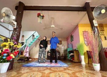 ROSLAN Yahaya (kanan) bersama anaknya, Siti Nursafwani melihat tiang  kayu daripada pokok berusia lebih 120 tahun yang masih kekal utuh di rumahnya di Kampung Hujung Tanjung, Seberang Ramai, Kuala Perlis, semalam. – UTUSAN/ASYRAF MUHAMMAD