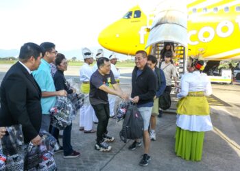 LOH Sze Yee (kiri) menyambut pelancong yang tiba menerusi penerbangan pertama sempena Tahun Melawat Perak (TMP) 2024 di LTSAS di Ipoh hari ini. - UTUSAN/MUHAMAD NAZREEN SYAH MUSTHAFA
