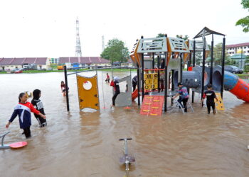Kanak-kanak bermain di taman permainan yang dinaiki air berikutan hujan lebat seolah-olah berada di taman tema air di Desa Mutiara, Johor Bahru disini. UTUSAN/RAJA JAAFAR ALI