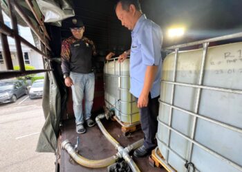 MUHAMMAD Zahir Mazlan (kanan) memeriksa tangki IBC yang terdapat di atas sebuah lori yang diperiksa dalam serbuan Op Tiris 3.0 di sebuah stesen minyak di Rembau, awal pagi tadi.