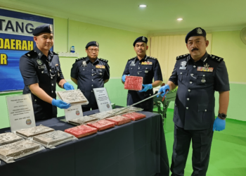 BADERULHISHAM BAHARUDIN (kanan) menunjukkan ketulan mampat ganja yang dirampas berdekatan pagar sempadan di Kampung Melayu, Padang Besar di Perlis hari ini. -UTUSAN/SYED AZLAN SAYID HIZAR