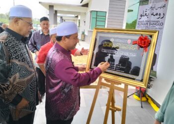 MOHD. Nassuruddin Daud (kanan) menandatangani plak penyerahan rumah kepada johan tilawah peringkat antarabangsa Muhammad Qayyim Nizar Sarimi di Wadi Iman Eksklusif di Tanah Merah, Kelantan - UTUSAN/ROHANA ISMAIL