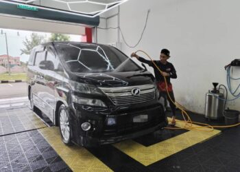 SEORANG pekerja mencuci kereta pelanggan di pusat mencuci kenderaan di Kampung Bukit Keluang, Besut, semalam. - UTUSAN/WAN ZURATIKAH IFFAH WAN ZULKIFLI
