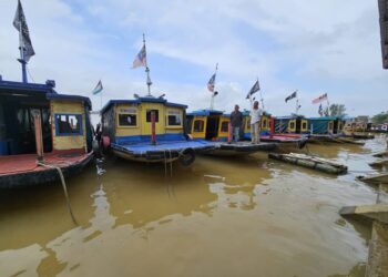 GHAZALI Abdullah (kiri) dan Hashim Ibrahim merenung masa depan apabila perkhidmatan bot penambang semakin tidak mendapat sambutan di Seberang Takir, Kuala Nerus, semalam. - UTUSAN/ZAID MOHD. NOOR