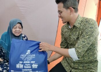 ROGAYAH LAMOR ketika ditemui Pengerusi Jawatankuasa Hal Ehwal Agama Negeri Johor, Mohd Fared Mohd Khalid di pusat pemindahan sementara PPS Sekolah Kebangsaan Bukit Kuari di Ayer Hitam semalam.