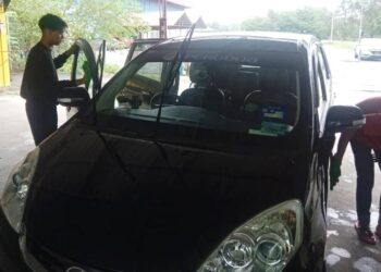 DUA pekerja mencuci kereta di sebuah kedai cucian  kenderaan di Kampung Gong Badak, Kuala Nerus, semalam.