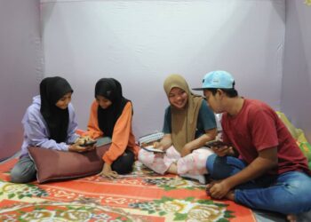 Empat pelajar mangsa banjir yang akan menduduki peperiksaan SPM dari kanan Muhd Aidil Haqimi  Abu Bakar, Nor Syahirah Azrin, Nurwahida Roslim dan Nursuhada Roslim mengulangi mata pelajaran dengan menggunakan telefon bimbit di PPS Dewan Muafakat Kampung Cahaya Baru Masai disini. UTUSAN/RAJA JAAFAR ALI