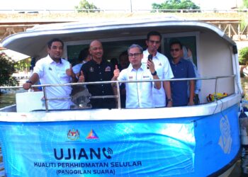 FAHMI Fadzil bersama Fairul Nizam Roslan (dua dari kiri) ketika melakukan Ujian Kualiti Perkhidmatan Selular (panggilan suara) dengan  menaiki Bot Melaka River Cruise di Melaka, hari ini. UTUSAN/AMRAN MULUP