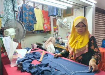 MAISARAH Long menyiapkan tempahan jahitan pakaian pelanggan yang perlu disiapkan sebelum sambutan Hari Raya Aidilfitri di Kuala Terengganu, semalam. - UTUSAN/KAMALIZA KAMARUDDIN