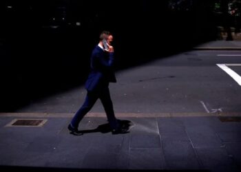 SEORANG ahli perniagaan bercakap menggunakan Apple iPhonenya semasa dia berjalan di sepanjang jalan di daerah pusat perniagaan (CBD) Sydney di Australia.-REUTERS