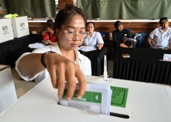 SEORANG wanita membuang undi di Pusat Pengundian Banjar Teba di pulau peranginan Bali, Indonesia.-AFP