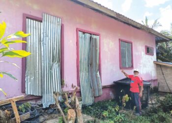 MOHD. Zain Ali menunjukkan tingkap dan pintu rumahnya yang terpaksa ditutup dengan zink bagi mengelak ancaman lotong serta kera liar di Kampung Tanjung Kala, Kuala Krai, Kelantan. - UTUSAN/AIMUNI TUAN LAH.