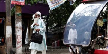 PENDUDUK berjalan melepasi sebuah tuk tuk di daerah Dhubri, Assam di India. - REUTERS
