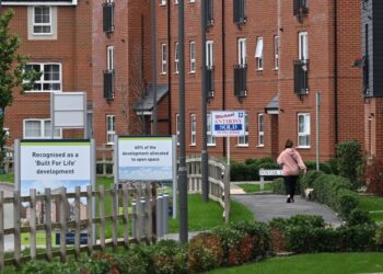 PENDUDUK berjalan melepasi kediaman baharu dibina di tapak pembinaan Barratt dan David Wilson berhampiran Aylesbury. - AFP