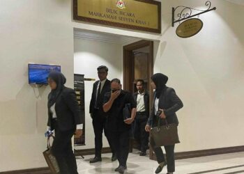 TERTUDUH (tengah) ketika diiring keluar dari Mahkamah Khas Rasuah di Kota Kinabalu hari ini.
