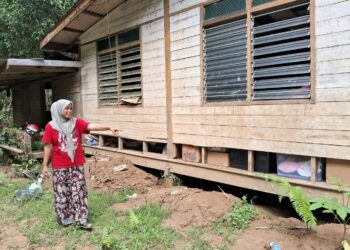 SALINAWATI Saleh menunjukkan keadaan lantai rumahnya yang senget dan rosak akibat banjir di Kampung Pasir Raja, Hulu Dungun, Dungun, semalam. - UTUSAN/NIK NUR IZZATUL HAZWANI NIK ADNAN