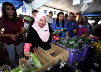 LILIS SASLINDA Pornomo (dua dari kanan) melihat sayur-sayuran yang dijual sempena Jualan Rahmah Tahun Baharu Cina di Blok 56, Flat Taman Ungku Tun Aminah, Johor Bahru.
