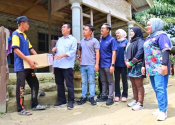 PENDUDUK Kampung Rekoh, Kamaruddin Puteh, 53, menerima sumbangan bantuan banjir disampaikan Abdul Khalib Abdullah (dua dari kiri) di Kampung Rekoh, Keratong di Rompin, Pahang. - UTUSAN/SHAIKH AHMAD RAZIF