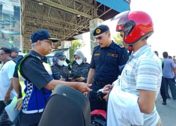 LOKMAN Jamaan memeriksa sebuah motosikal yang ditunggang seorang warga asing ketika Ops Khas Musim Perayaan Tahun Baharu Cina di Jambatan Sultan Mahmud, Kuala Terengganu hari ini. - UTUSAN/TENGKU DANISH BAHRI TENGKU YUSOFF