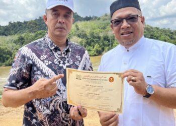 MOHD. JAFRI Zainal Abidin (kiri) menyampaikan sijil wakaf tanah miliknya kepada Zuhairi Ab. Kadir di Kampung Mentenang, Chenor di Maran, Pahang.