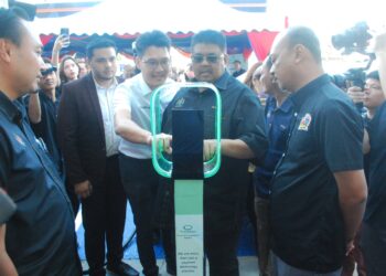 AB. Rauf Yusoh mencuba menggunakan mesin pembayar selepas merasmikan EV Charging Hub di Jalan Gajah Berang, Melaka, hari ini. - UTUSAN/AMRAN MULUP