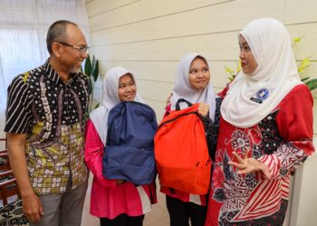 PUTRI Maisarah Bahari (dua dari kiri) dan Putri Rabiatul Adawiyah (dua dari kanan)  menerima sumbangan kelengkapan sekolah daripada Gas Malaysia, semalam.- UTUSAN/SADDAM YUSOFF