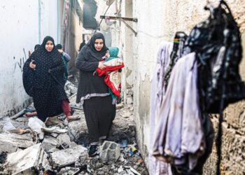 ORANG ramai melalui lorong yang dilitupi runtuhan selepas pengeboman Israel di Rafah, selatan Gaza, semalam. - AFP