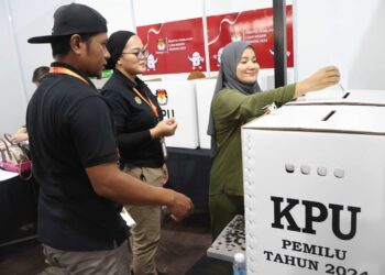 SEORANG warga Indonesia (kanan) tidak melepaskan peluang untuk membuang undi pada hari pengundian awal Pemilu di Konsulat Jenderal Republik Indonesia Pulau Pinang di Jalan Burmah, Pulau Pinang. - UTUSAN/IQBAL HAMDAN