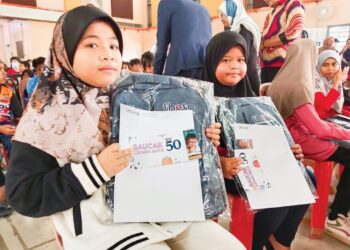 DUA murid menunjukkan beg sekolah dan baucar yang diterima dalam program Kembali Ke Sekolah 2024 di Kompleks Japerun Duyong, Melaka. – UTUSAN/MUHAMMAD SHAHIZAM TAZALI