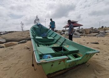 DUA nelayan melihat bot mereka yang rosak akibat dipukul ombak besar di Seberang Takir, Kuala Nerus, Terengganu, semalam. – UTUSAN/KAMALIZA KAMARUDDIN
