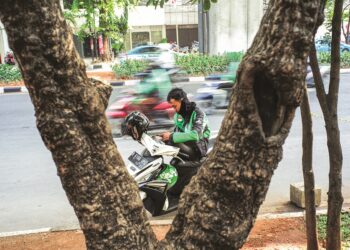Seorang penunggang ‘Ojek’ teksi motosikal menunggu pelanggan di sebatang jalan di Jakarta, ibu negara Indonesia. - AFP
