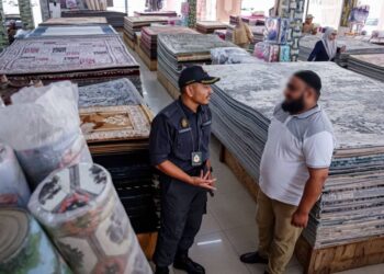 ANGGOTA penguat kuasa KPDN menyoal seorang peniaga di premis perniagaan sekitar MITC, Ayer Keroh, Melaka. - UTUSAN/SYAFEEQ AHMAD