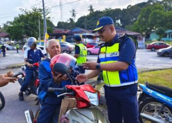 MUHAMMAD FIRDAUS Shariff memberikan topi keledar baharu kepada seorang penunggang motosikal di Masjid Tanah, Alor Gajah, Melaka.