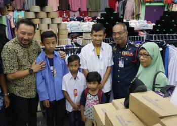 AHMAD Izram Osman (dua dari kanan) bersama empat daripada lima anak anggota bomba yang maut ketika sedang menyelenggara bot di Butterworth minggu lepas memilih pakaian sekolah di Pusat Pakaian Hari-Hari, Bandar Perda, Bukit Mertajam, Pulau Pinang.-UTUSAN/IQBAL HAMDAN