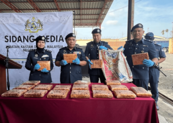 ISMAIL Hashim (dua dari kiri) menunjukkan ketulan mampat ganja yang ditemukan dalam satu bungkusan guni di perairan Sungai Belati, Kuala Perlis, Khamis lalu.- UTUSAN/ASYRAF MUHAMMAD