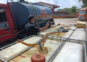 ANGGOTA KPDN memeriksan lori tangki berisi minyak dipercayai diesel bersubsidi dalam serbuan di sebuah premis di Kawasan Perindustrian IBG di Ipoh semalam. - UTUSAN/IHSAN KPDN