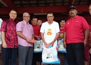 HASSAN (tiga, kiri) menyampaikan sumbangan makanan dan wang tunai kepada 30 keluarga B40 sempena sambutan Tahun Baru Cina di Tokong Kim Ying, Plentong, Pasir Gudang, hari ini.