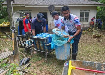 HAFIZ Ariffin (tengah) membantu membersihkan rumah  penduduk yang terjejas banjir di Kampung Jongok Batu, Hulu Dungun, Dungun, hari ini. - UTUSAN/PUQTRA HAIRRY ROSLI